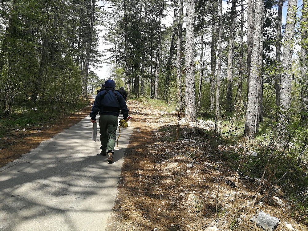 Deminers leaving the site after successful completion of activities, with the removed mine sign.